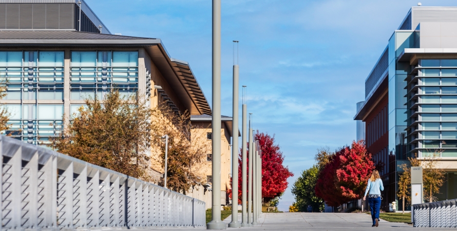 student walking on a pathway next to uc merced campus buildings